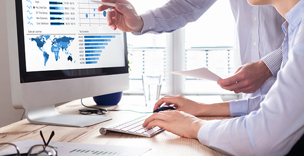 Two businessmen on a computer analyzing graphs from Minitab's business intelligence solutions software.