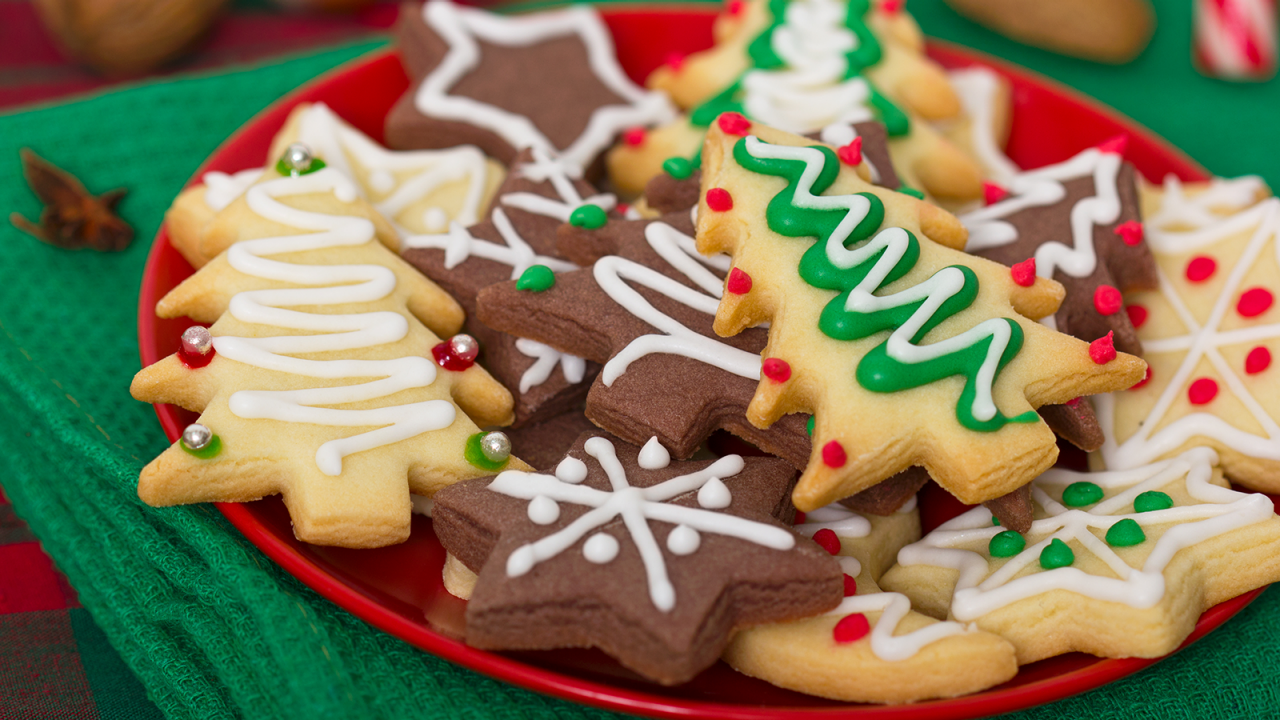 Roter Teller, dekoriert mit  Weihnachtskeksen auf einem grünen Tischtuch.