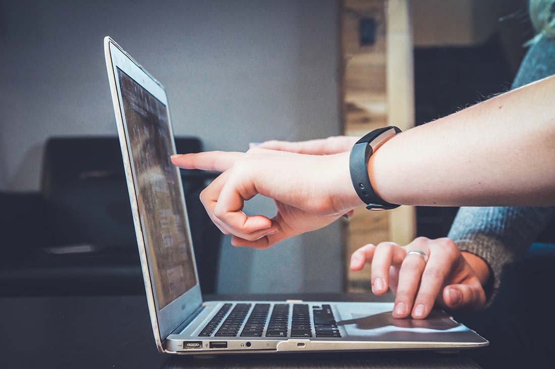 Two people analyzing customer feedback data on a laptop in a dark office.