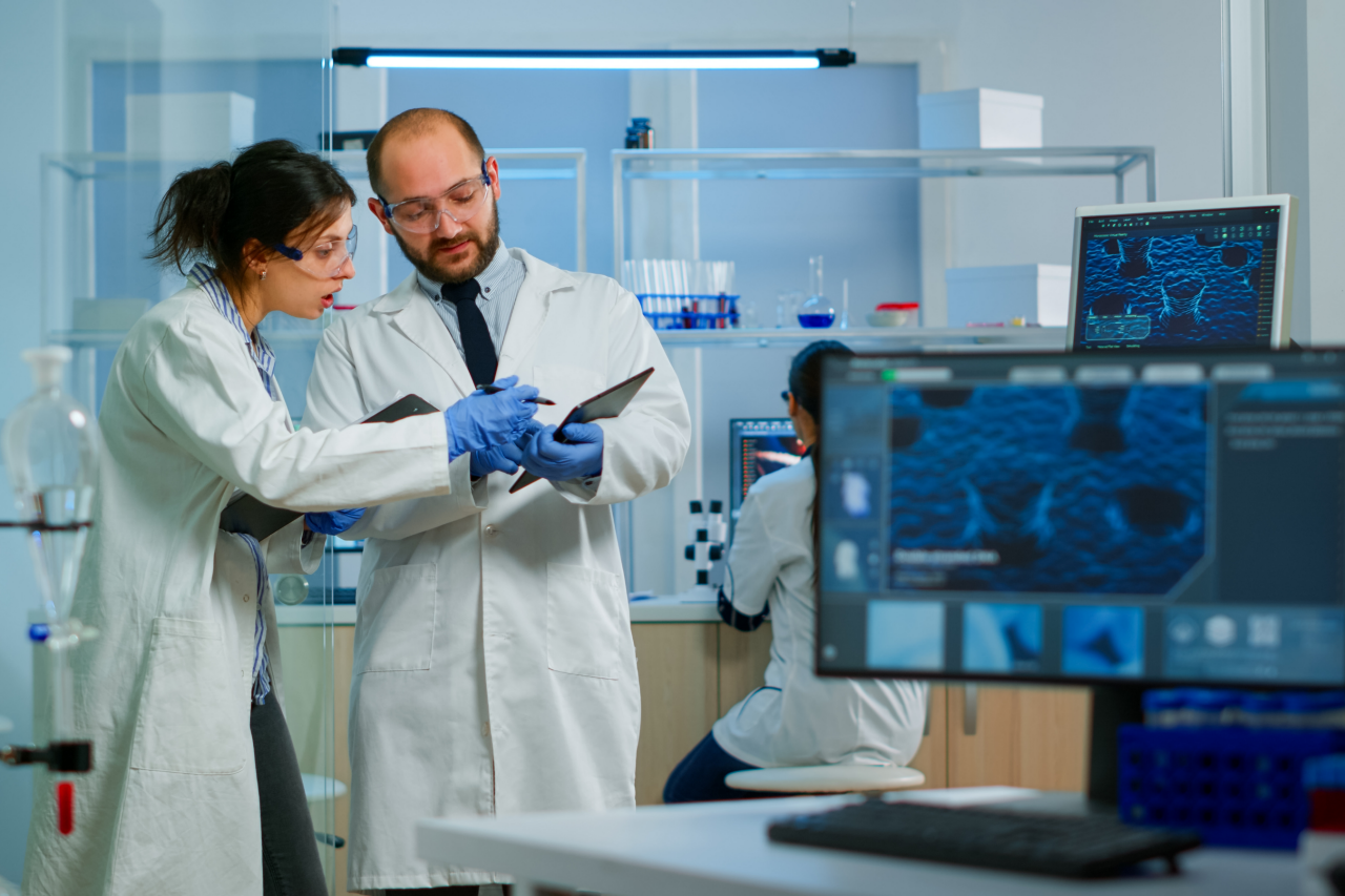 Laboratorio moderno de investigación médica: Dos científicos trabajando, analizando pruebas con una tableta digital y conversando. Laboratorio farmacéutico científico avanzado para medicina y desarrollo biotecnológico.